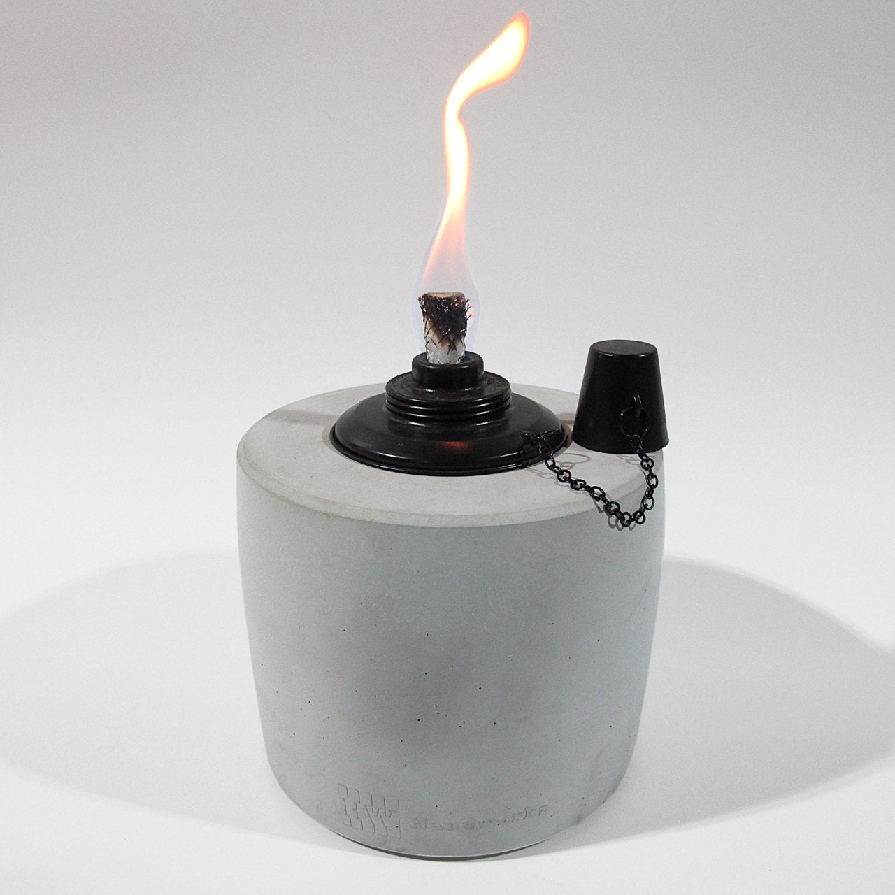 Öllampe in Grau mit 17cm Durchmesser und 20cm Höhe. Der schwarze Einsatz des Ölbrenners erzeugt eine schöne gleichmäßige Flame. Der Löschdeckel hängt an einer feinen Kette auf der rechten Seite.