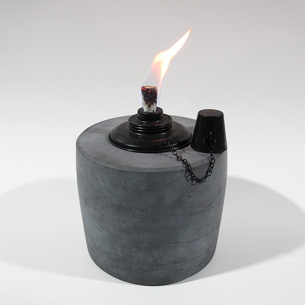 Fackel in Anthrazit mit 17cm Durchmesser und 20cm Höhe. Der schwarze Einsatz des Ölbrenners erzeugt eine schöne gleichmäßige Flame. Der Löschdeckel hängt an einer feinen Kette auf der rechten Seite herunter.